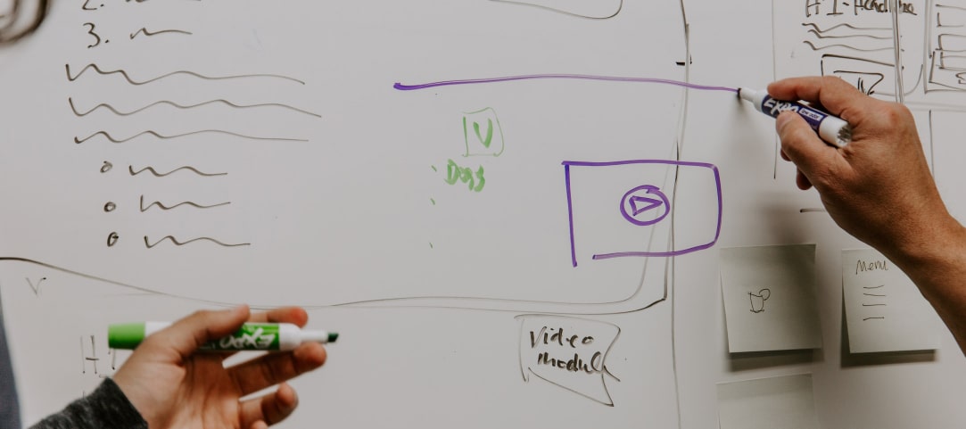 Hands writing ideas on a board